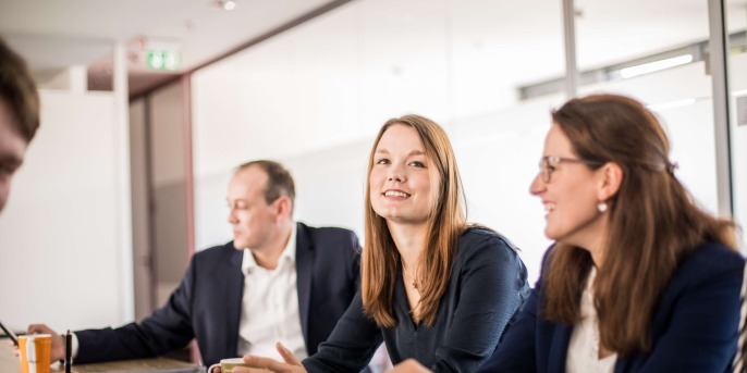 Photo of three adesso employees sitting at a table